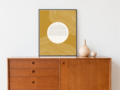 A rectangular modern art ketubah with gold and mustard yellow lines, displayed on a wall above a wooden cabinet with a decorative vase on top.